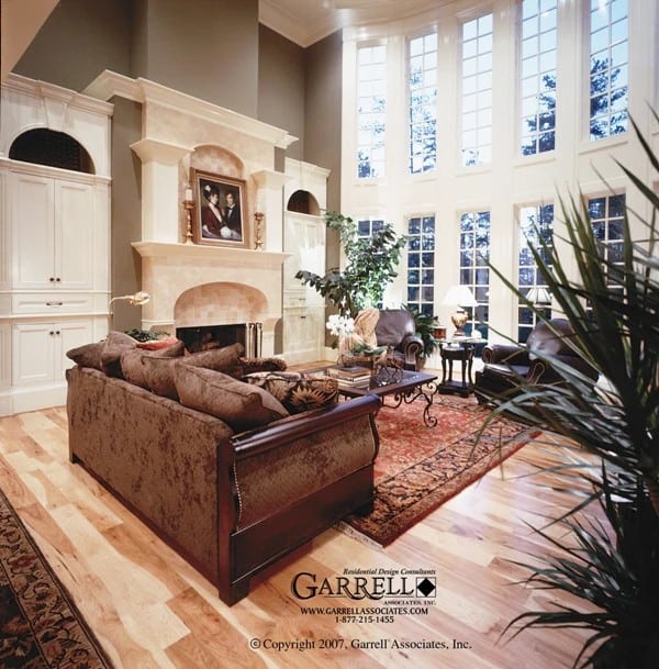 Living room with a velvet sofa, a fireplace, built-in cabinets, and a wall of windows allowing natural light in.