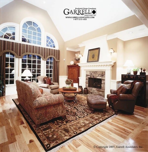 Family room with a vaulted ceiling, a stone fireplace, and mismatched seats over a tasseled area rug.