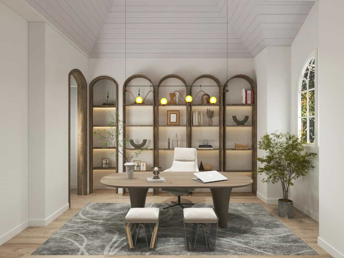 Home office with a vaulted ceiling, built-in bookshelves, and an oval desk complemented with beige chairs.