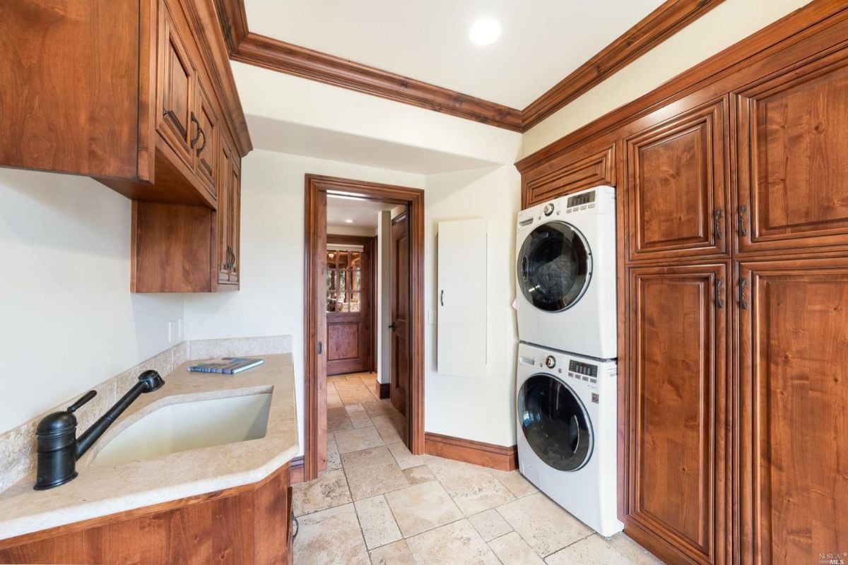 Laundry room with a sink and wooden cabinets.