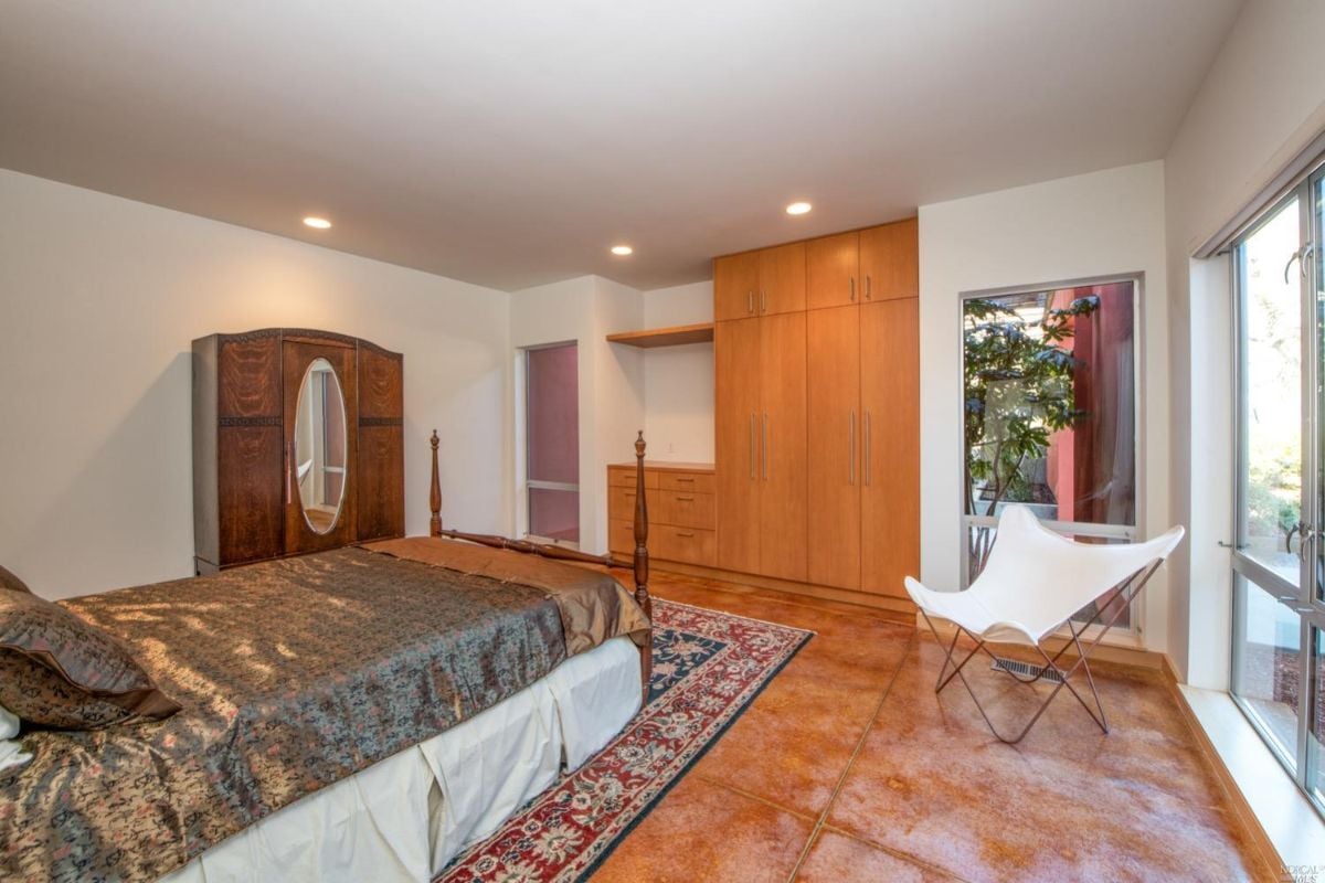 Bedroom with a rug, tiled floors and glass doors.