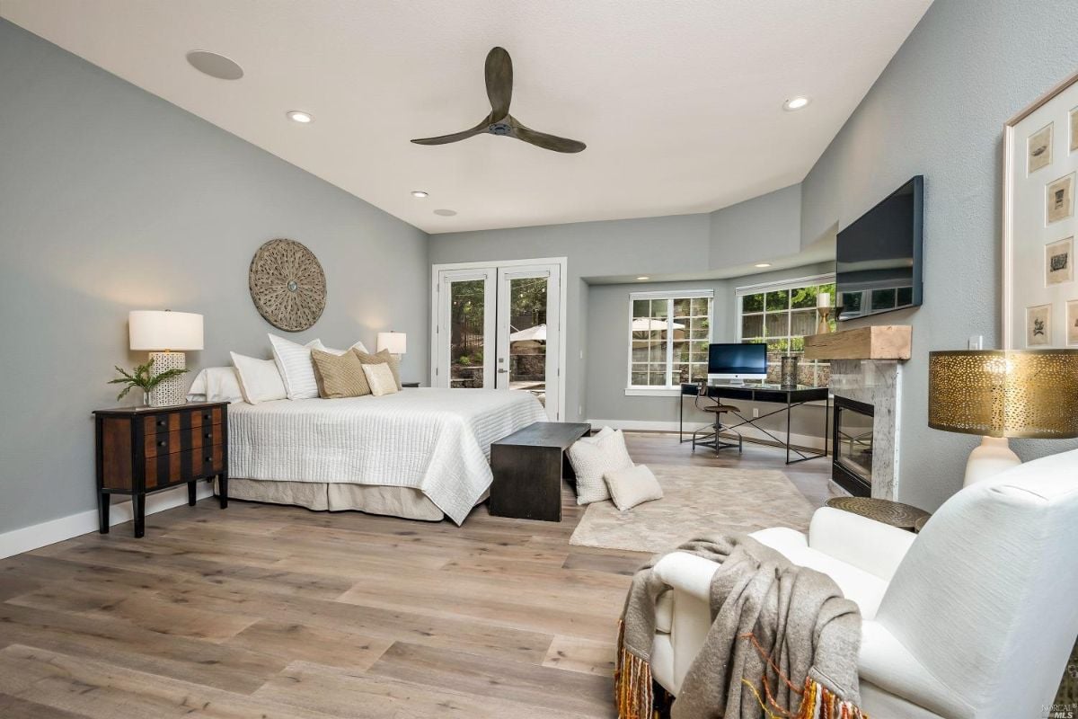 Bedroom with a fireplace, glass doors, glass windows, and TV.