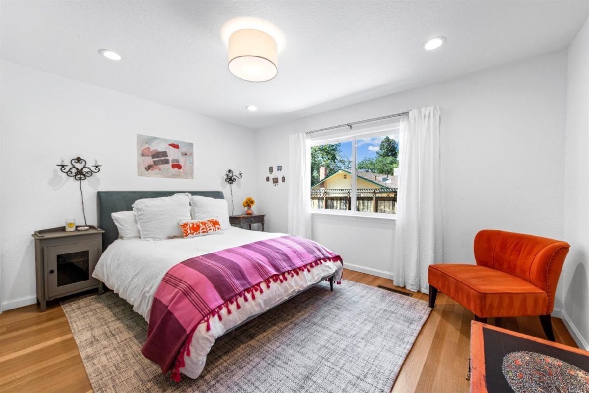 Bedroom with wooden flooring, rug and glass windows.