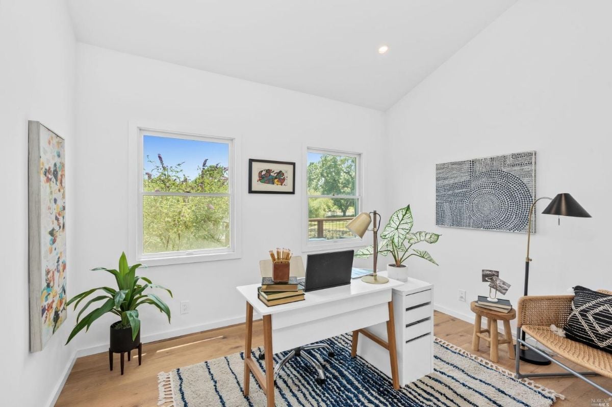 Home office with a rug, white walls and glass windows.