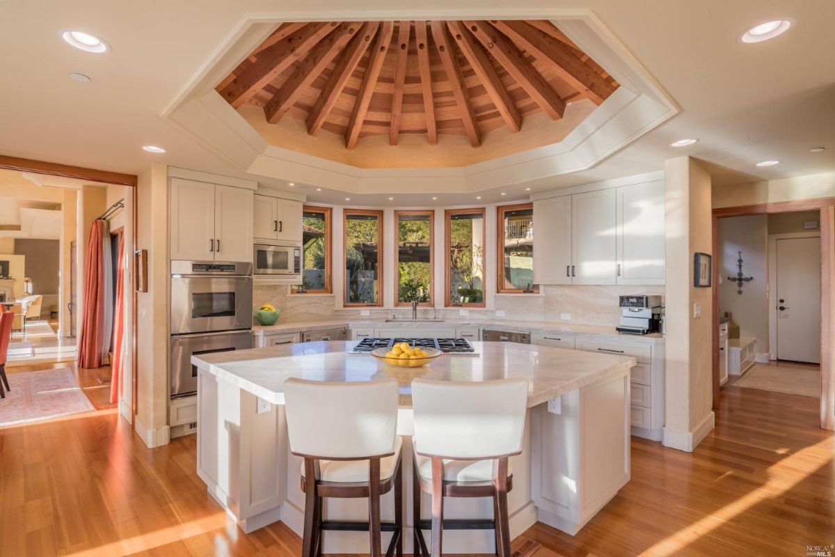 Kitchen with wood flooring, breakfast area, slab countertops, and custom lighting.