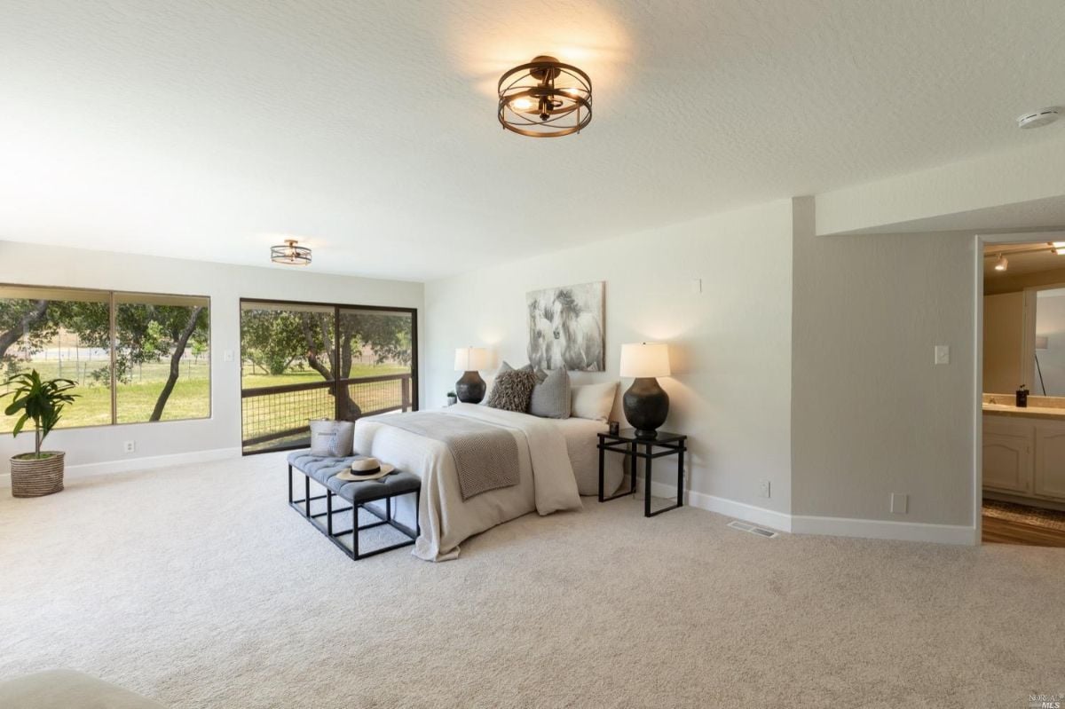 Carpeted bedroom with a a large window.