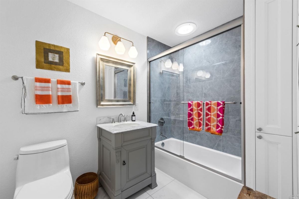 Bathroom with sink, tub over shower, and toilet.
