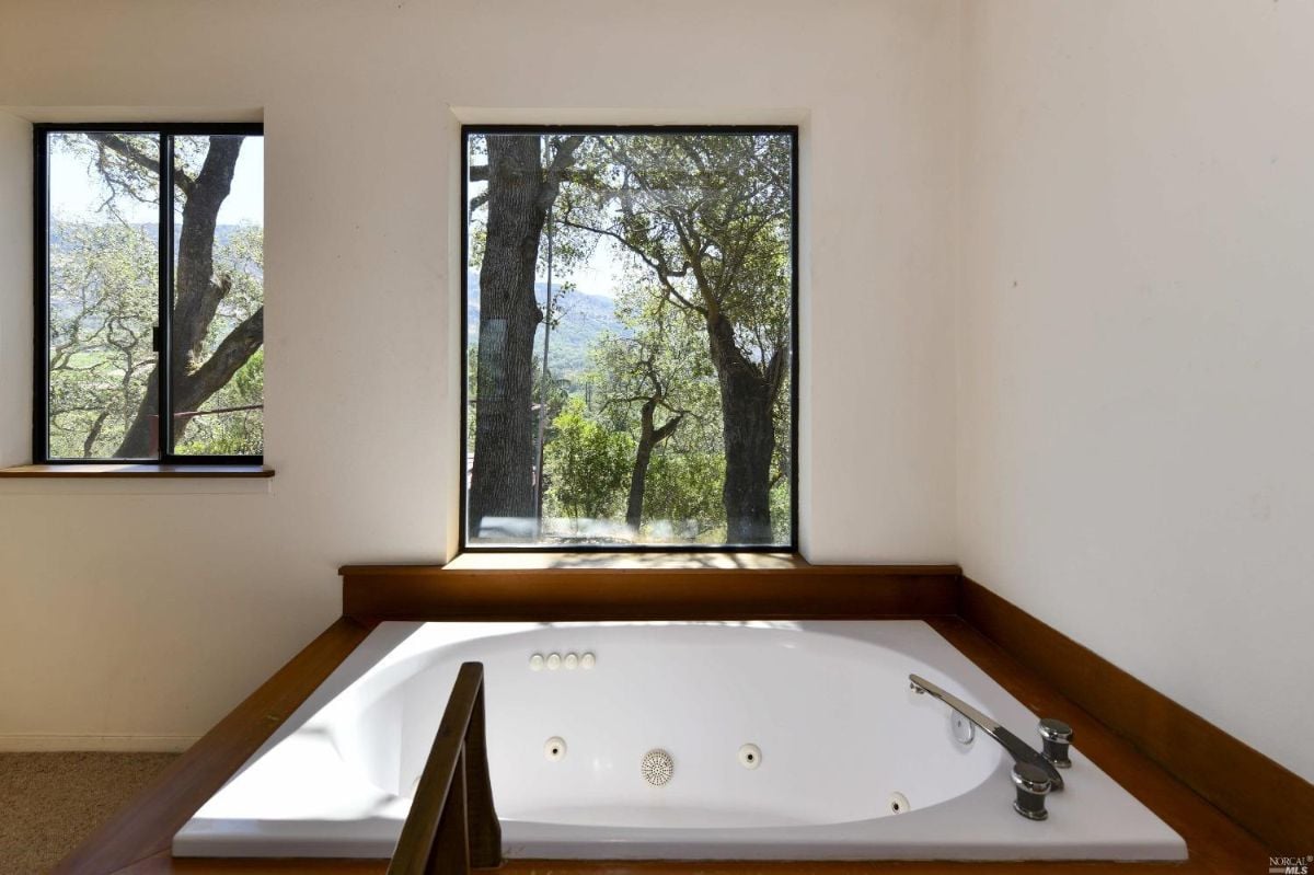 Bathroom with a bath tub and a view of the trees.