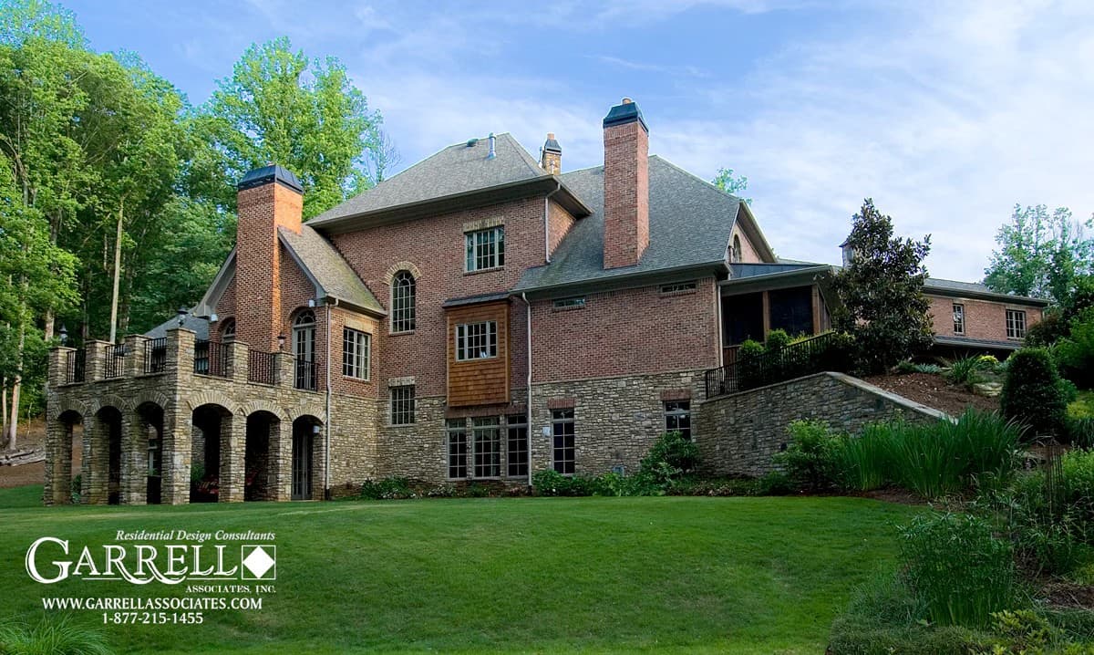 Rear view of the house showcasing its brick exterior, multiple chimneys, and a covered porch with a spacious deck on top.