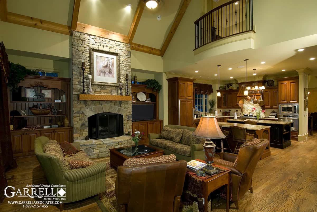 Keeping room with a stone fireplace, traditional seats, and a vaulted ceiling framed with exposed beams.