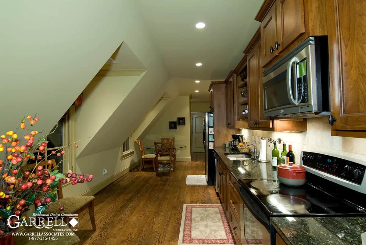 Bonus space with a round dining set and a kitchenette with wooden cabinets that blend in with the hardwood flooring.