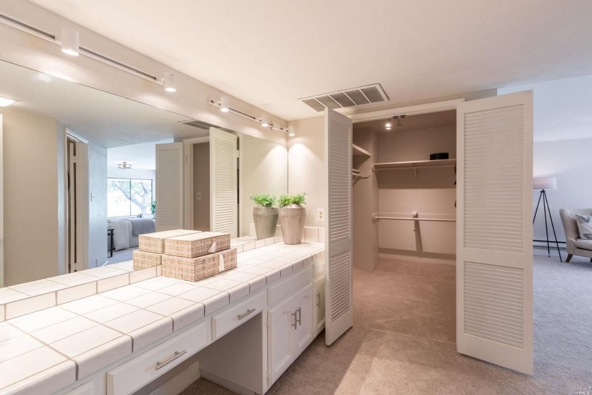 Walk-in closet with a mirror and a sink.