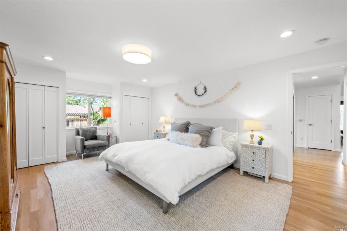 Bedroom with wooden flooring, rug and glass windows.