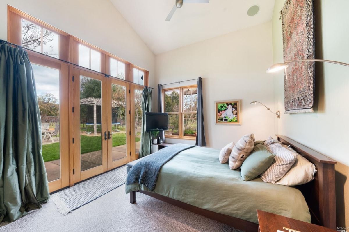 Carpeted bedroom with a TV and large glass doors.