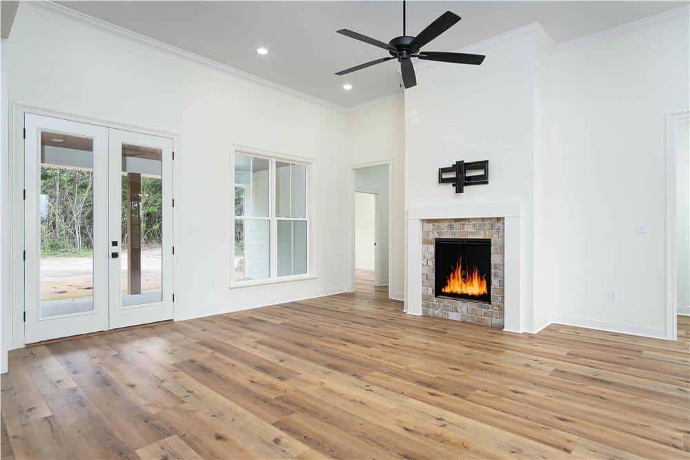 Great room with a stone fireplace and a wrought iron fan hanging from the white regular ceiling.