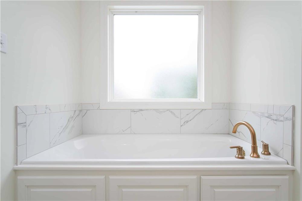 Primary bathroom with a drop-in bathtub illuminated by a picture window.