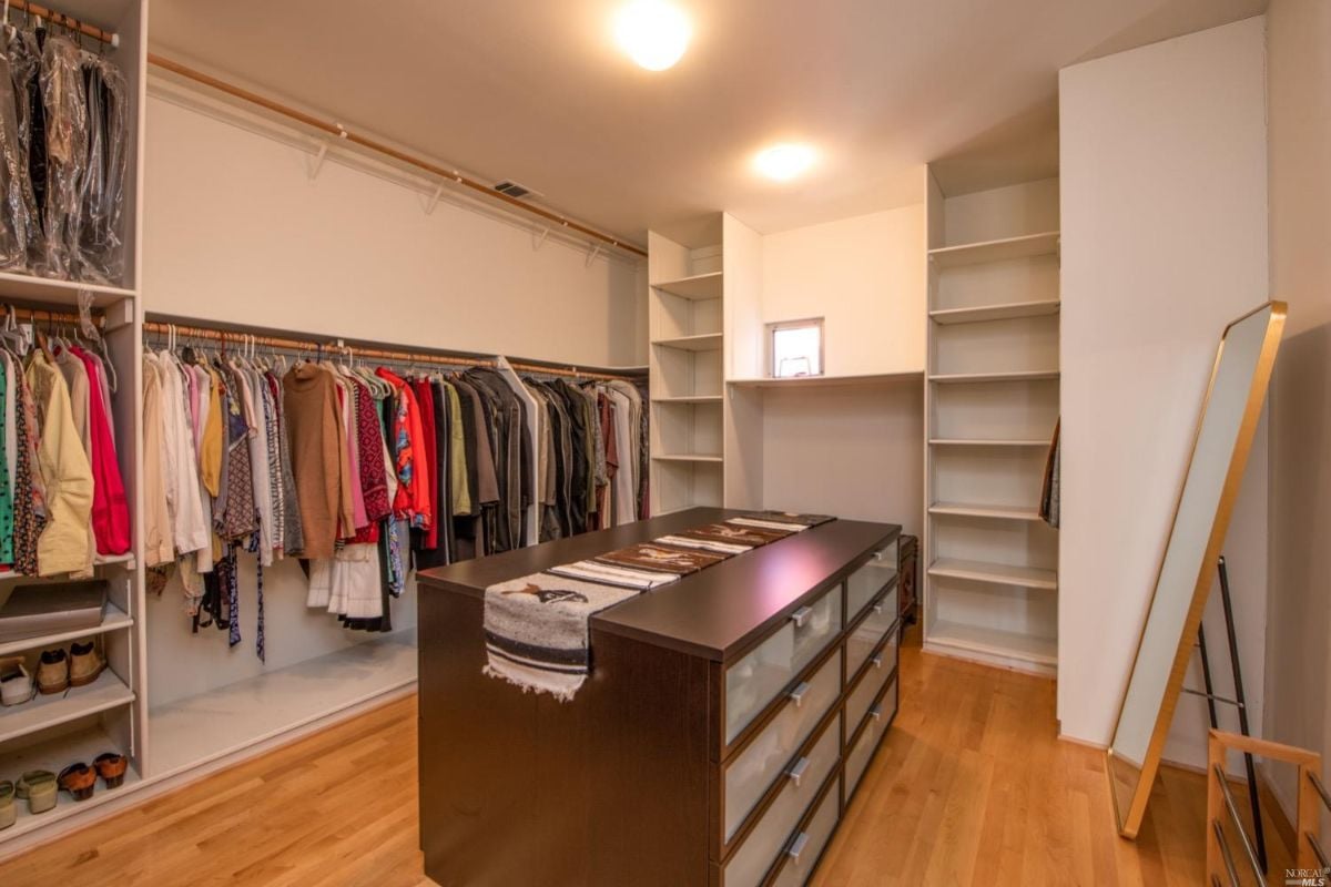 Walk-in closet with a wooden floor and shelves.