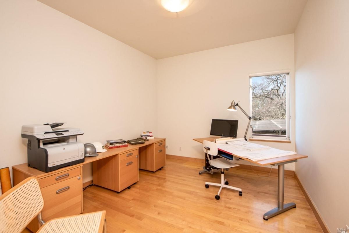 Home office with a wooden floor, desks, computer and chairs.