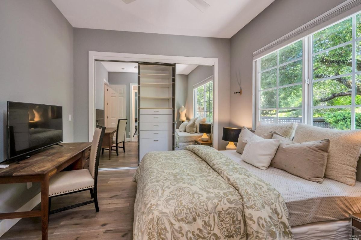 Bedroom with a flat screen TV, glass windows, and wood flooring.