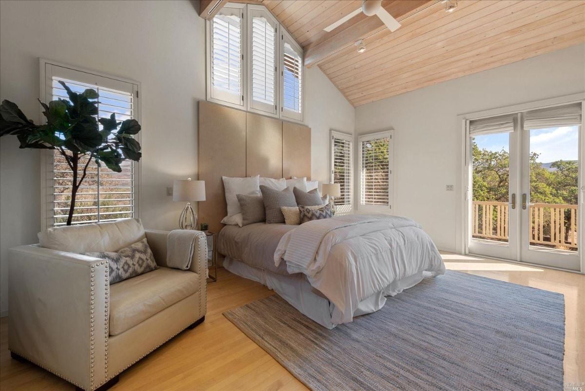 Bedroom with a rug, couch, Cathedral ceiling, and glass doors.