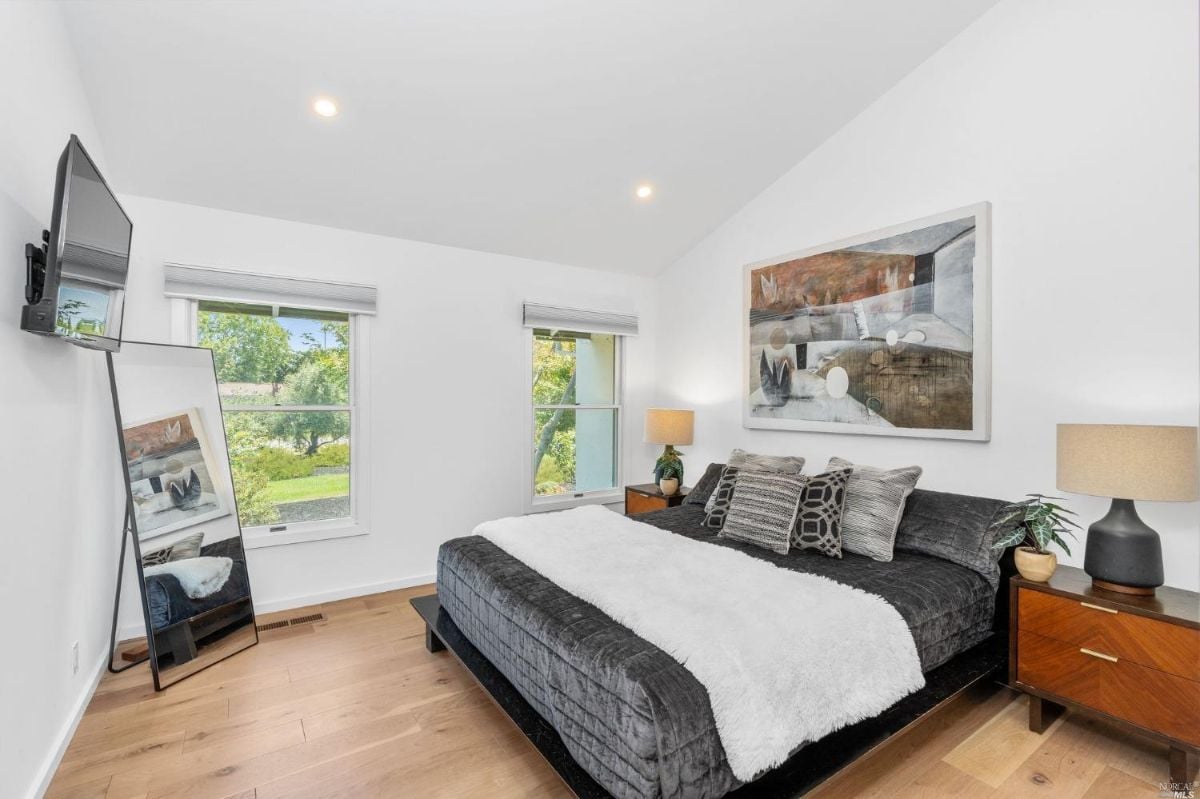 Bedroom with TV, glass windows, and wood floorings.