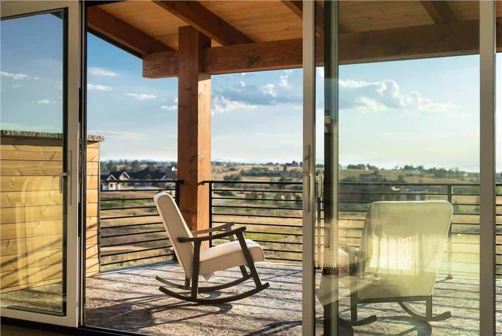 Covered deck with rocking chairs and expansive views of the surrounding landscape.