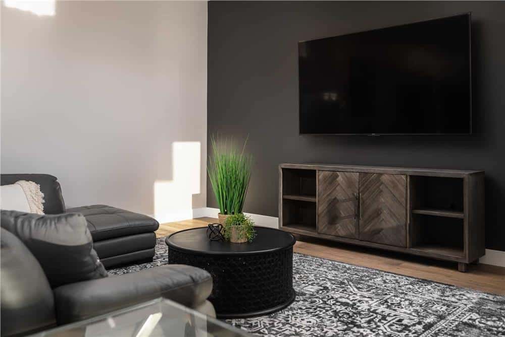 Media area with a large TV and leather seats paired with a round coffee table.