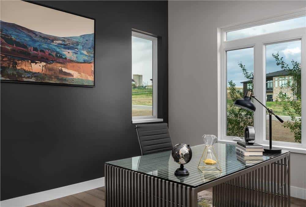Home office with contrasting walls and a wood slat desk paired with a black leather chair.