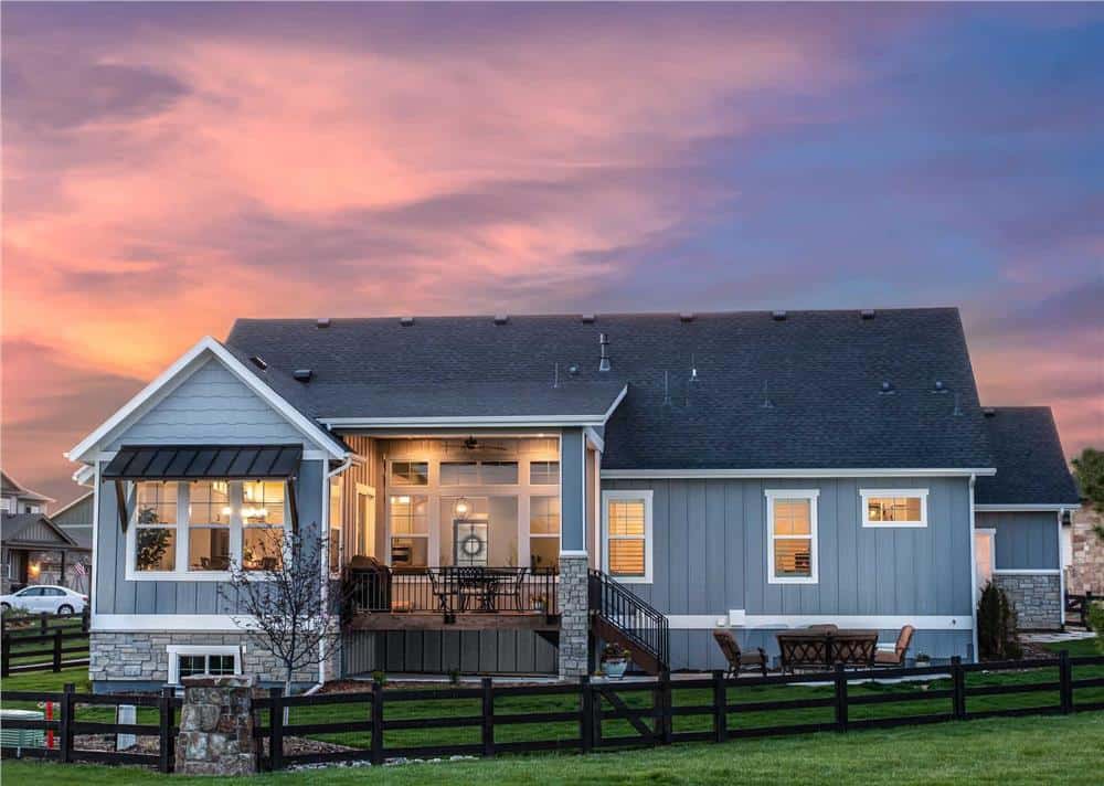 Rear view of the house showcasing its huge windows and a raised covered deck that transitions onto an open patio.