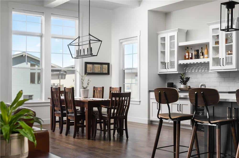 Dining area with huge windows and a 6-seated dining set topped by a linear chandelier.