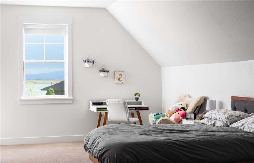 Secondary bedroom with a wooden desk and bed under a vaulted ceiling.
