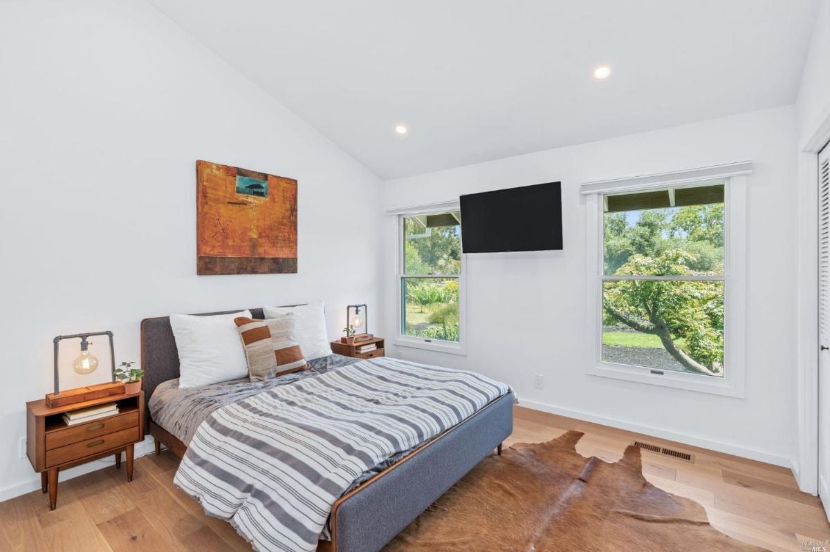 Bedroom with TV, glass windows, and wood floorings.