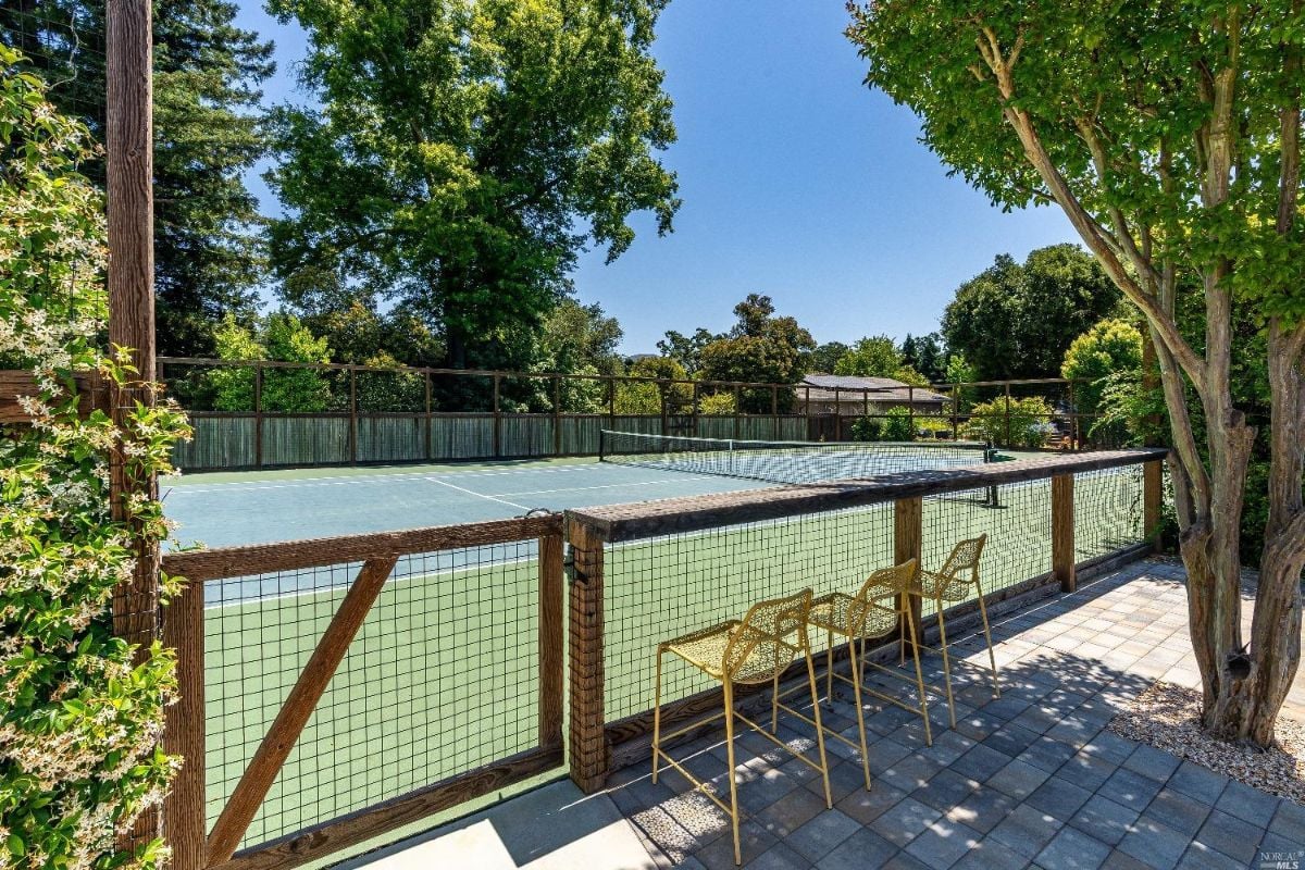 Spacious tennis court with trees around it.