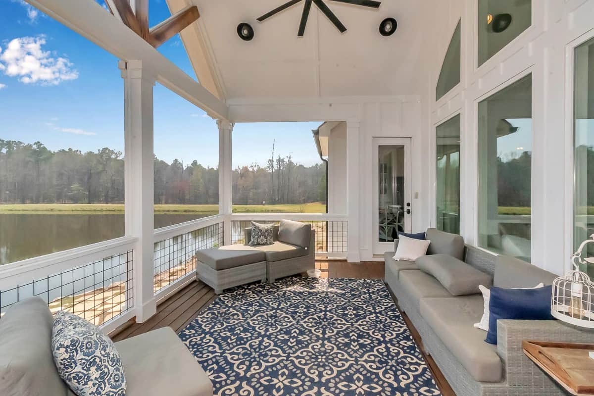 The covered porch offers gray seats and a spectacular view of the surrounding landscape.