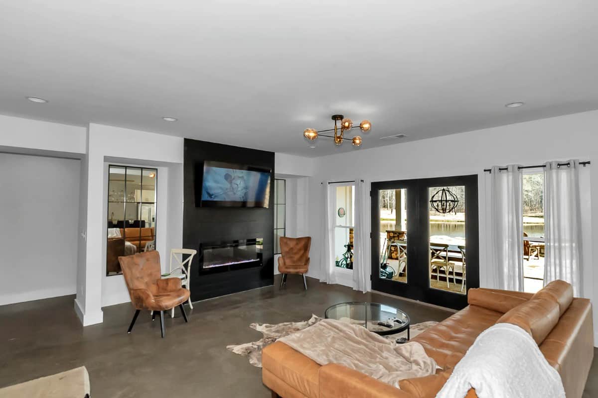 Lower-level grand room with leather seats, a modern fireplace, and a French door that opens onto the back porch.