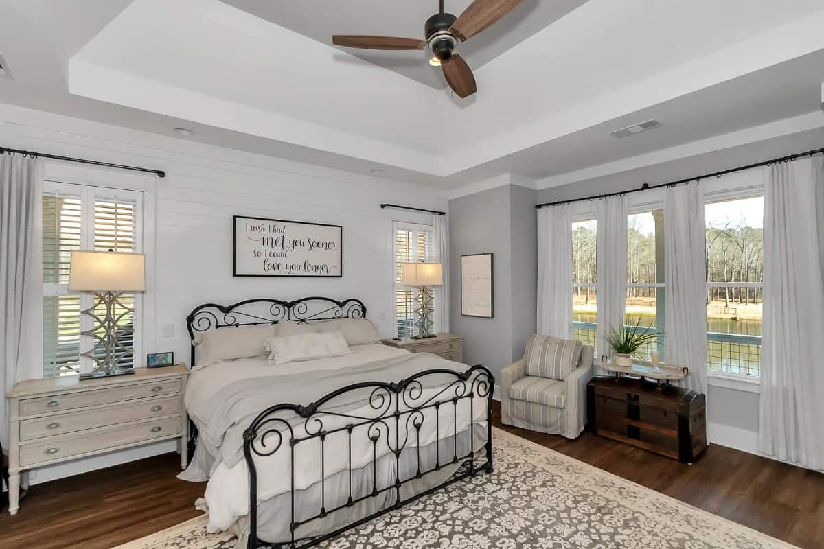 The primary bedroom features a tray ceiling and a sitting area by the boxed bay window.
