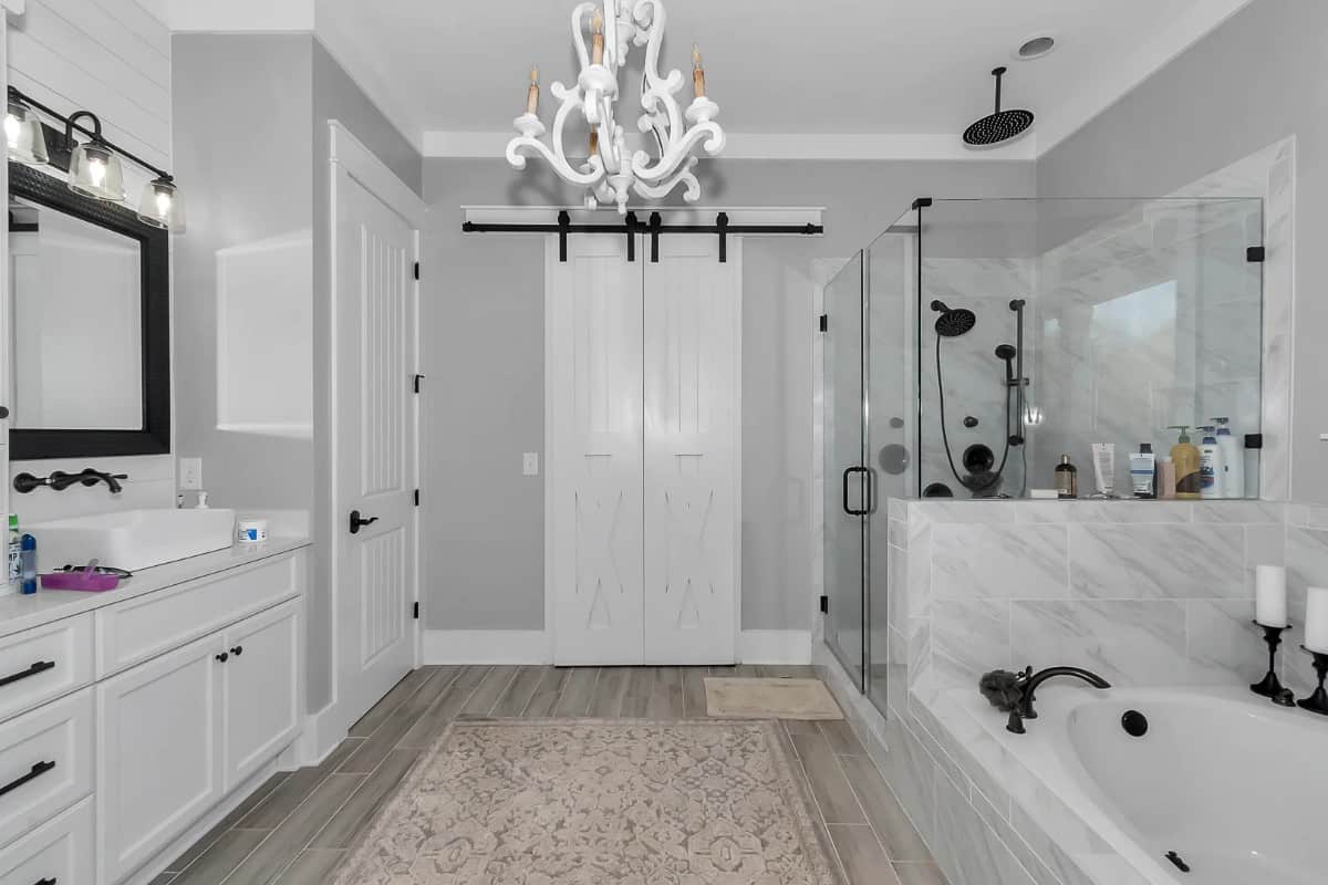 The primary bathroom offers a vessel sink vanity, a deep soaking tub, a tiled shower, and a walk-in closet concealed behind the double barn doors.