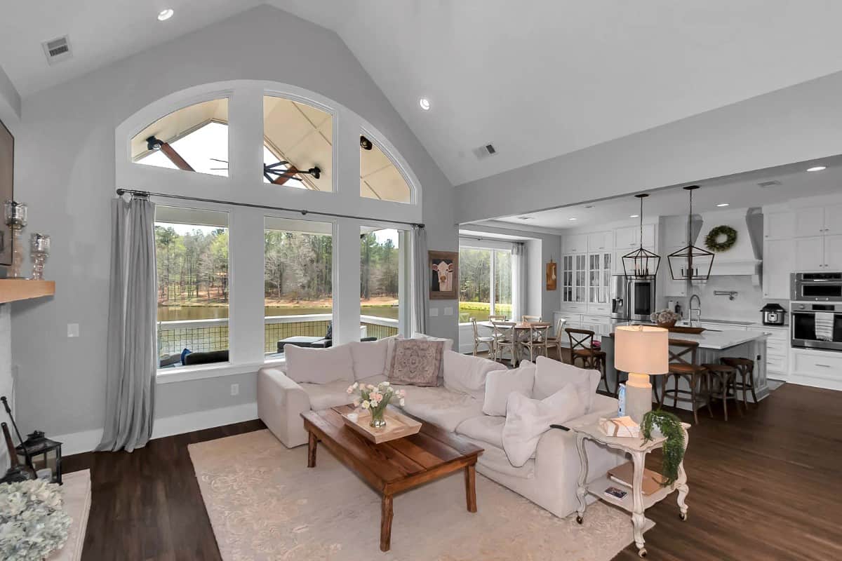Family room with a wall of windows, a vaulted ceiling, and an L-shaped sofa paired with a wooden coffee table.