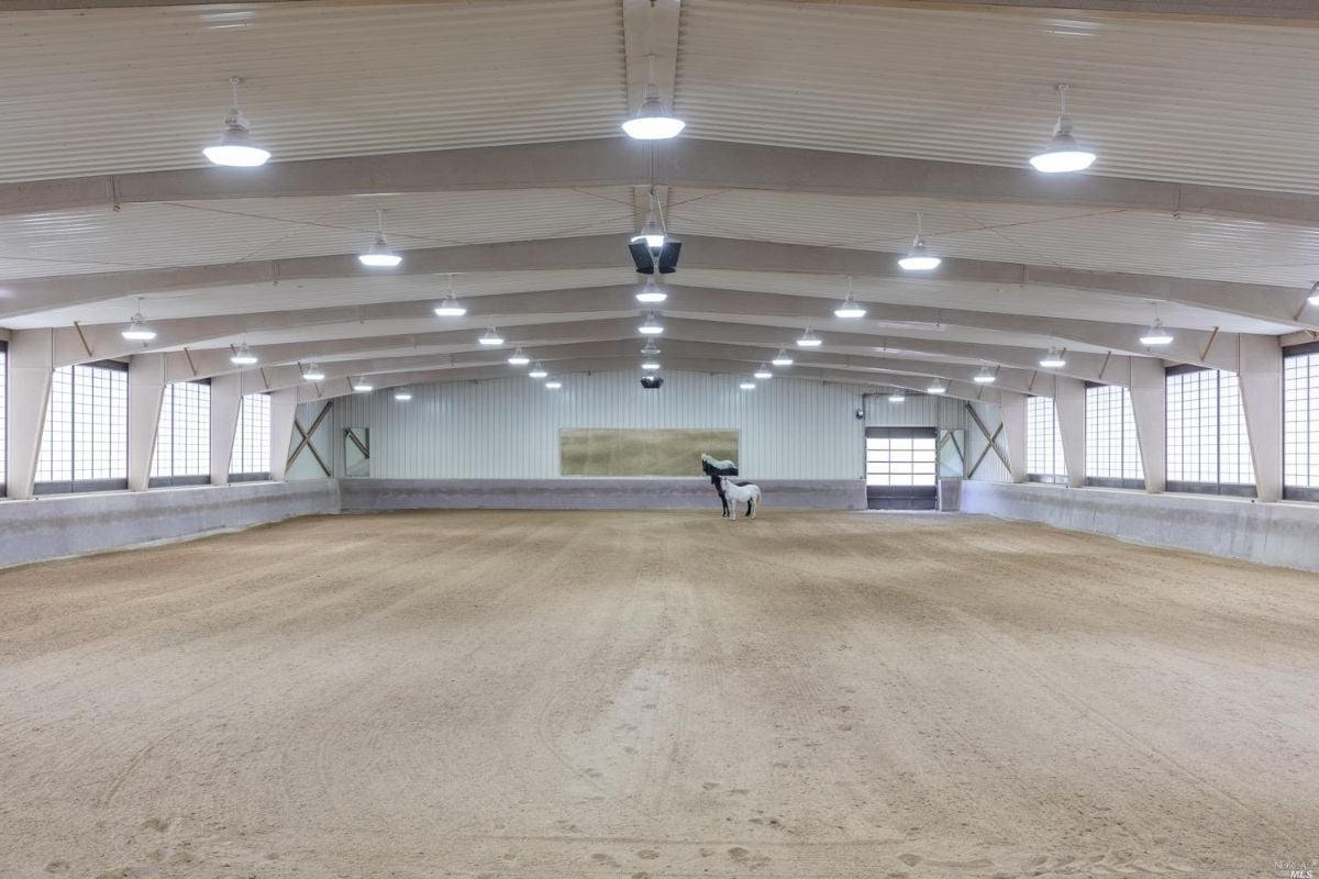 A well-lit, spacious horse barn.