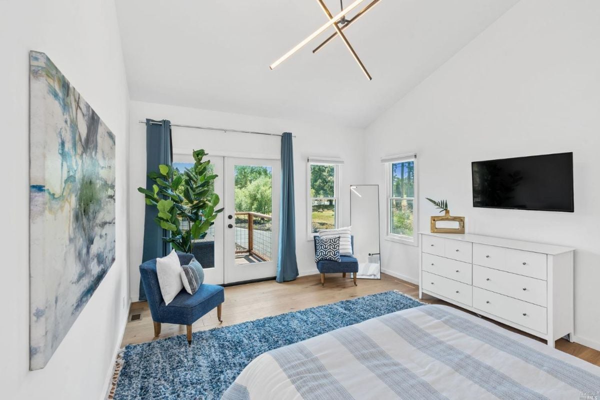 Bedroom with TV, glass windows, glass doors and wood floorings.