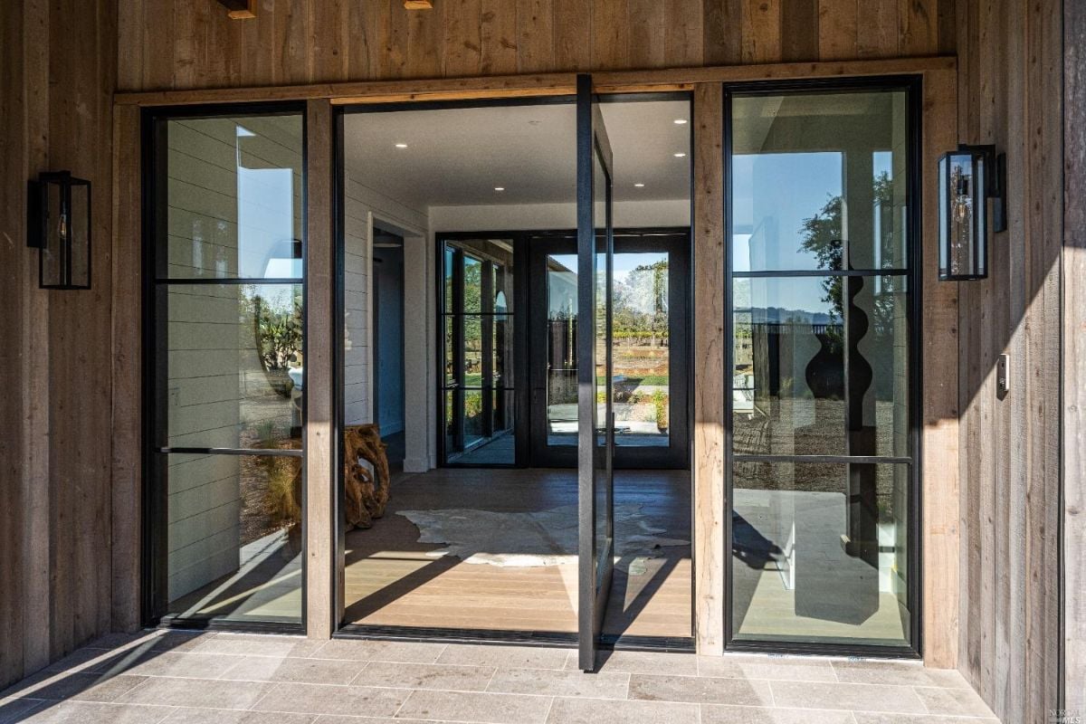 Formal entry with glass doors and wood walls.