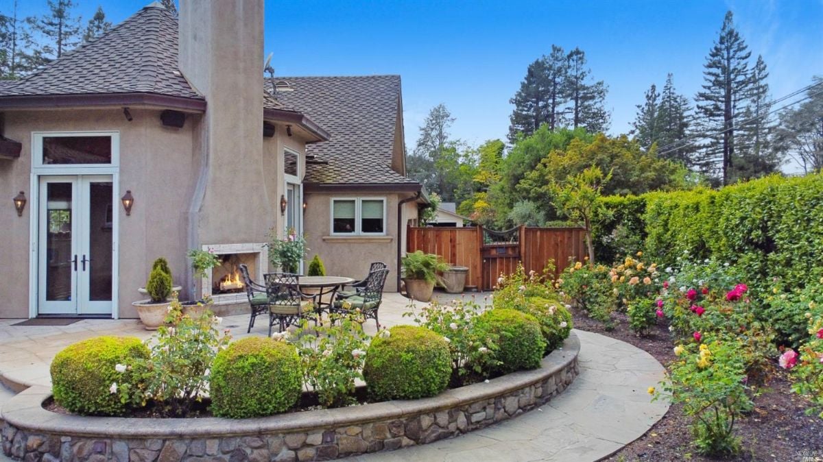 Patio with a fireplace and landscaping.