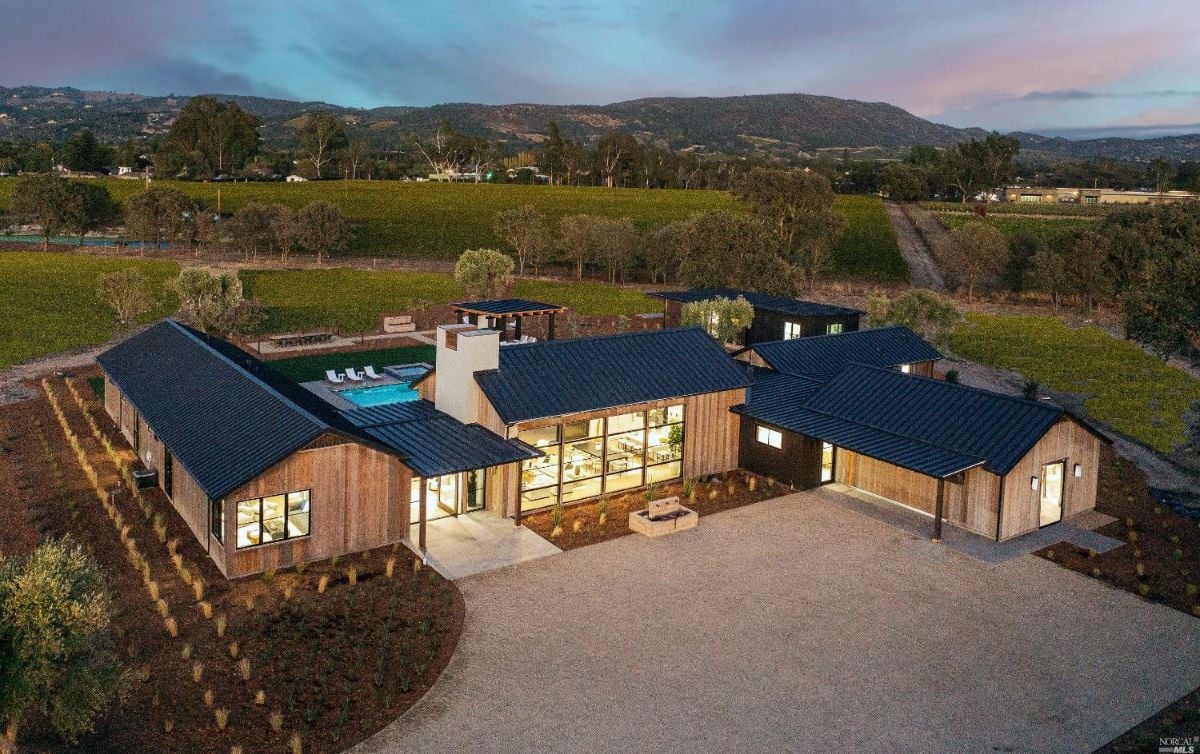 Aerial front view of the house with a vineyard in the background.