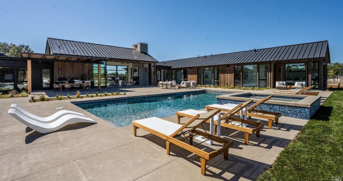 Rear view of the house with a pool and lounge chairs.