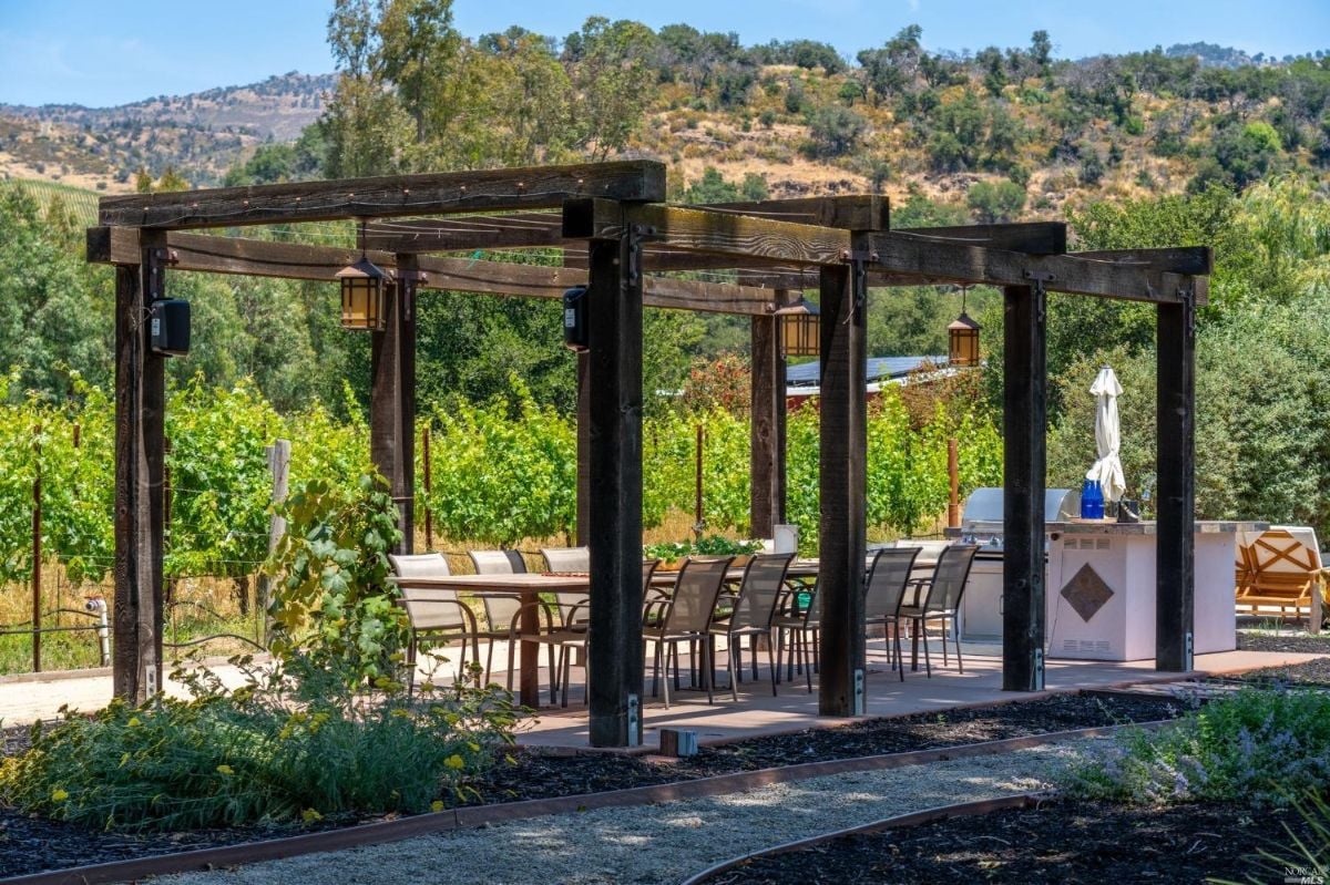 Patio with a grill, a table, and chairs.