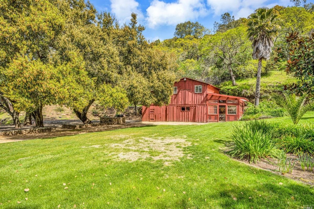 Red barn sits in the middle of a green field.