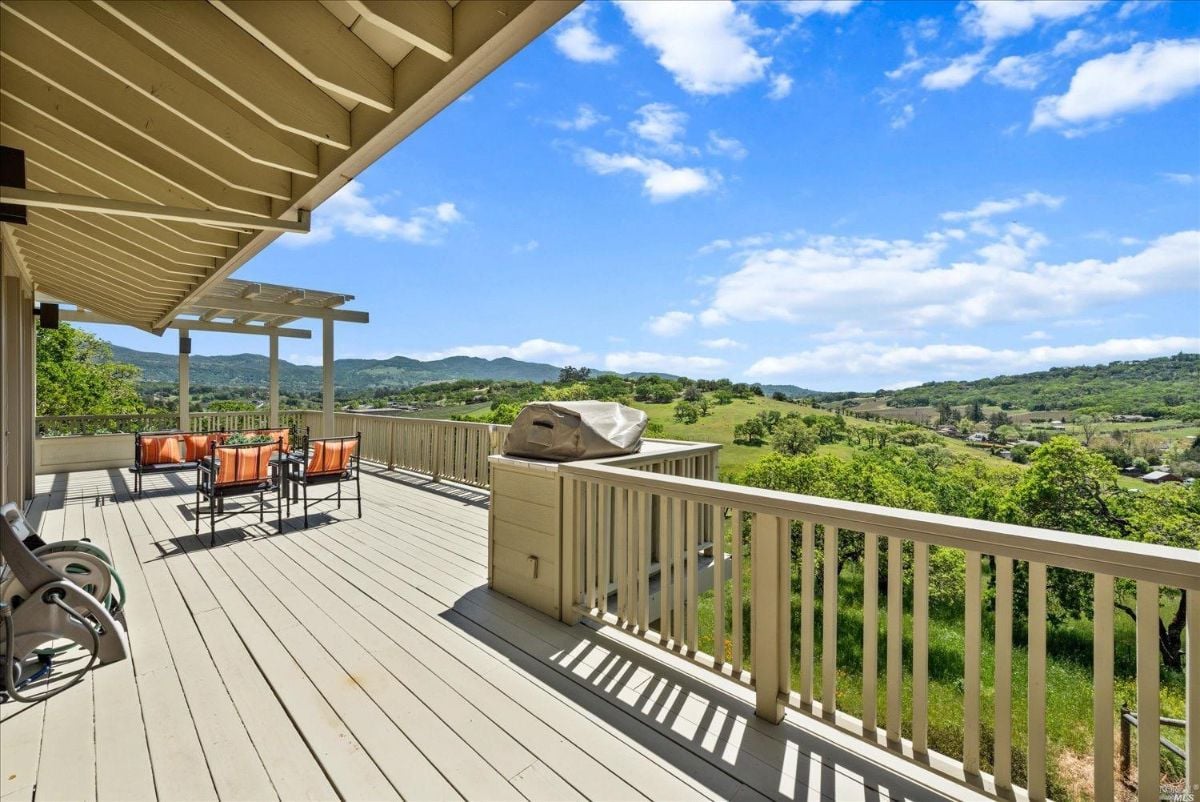 Balcony with chairs, table, and a view of the mountains.