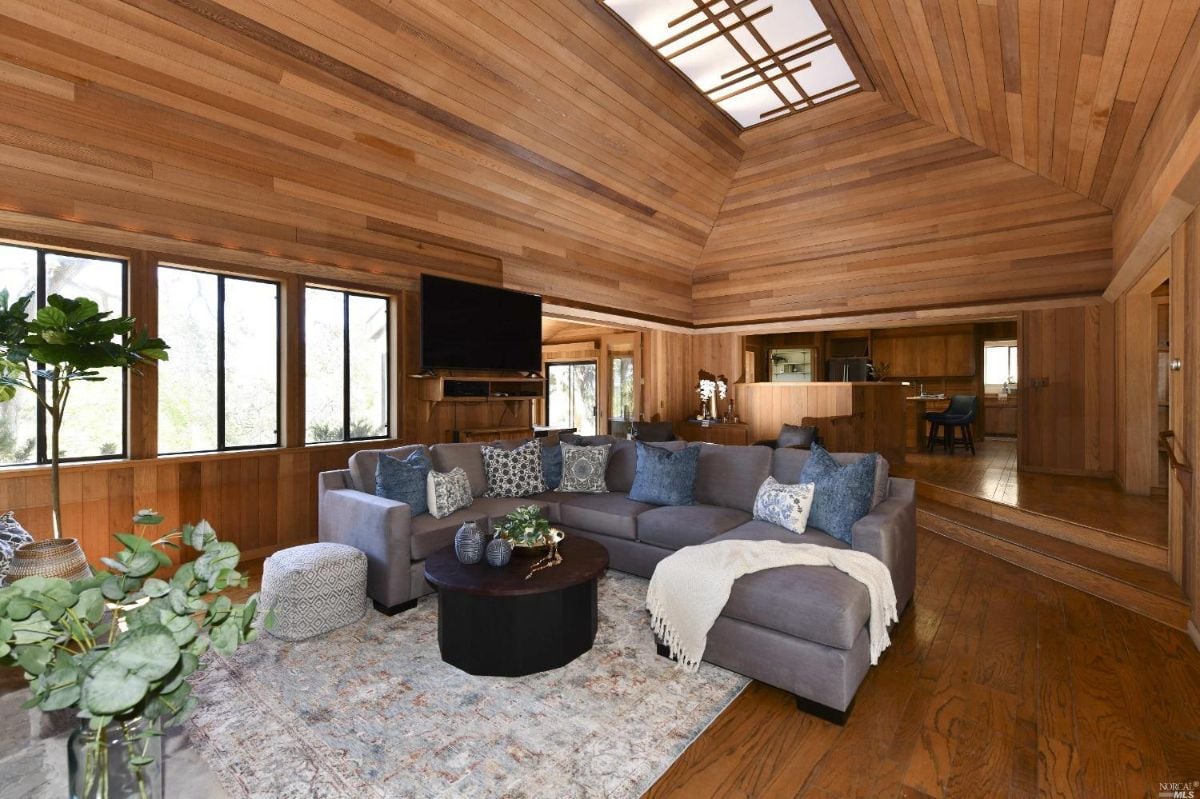 Living room with cathedral ceiling, wood flooring, and couches.