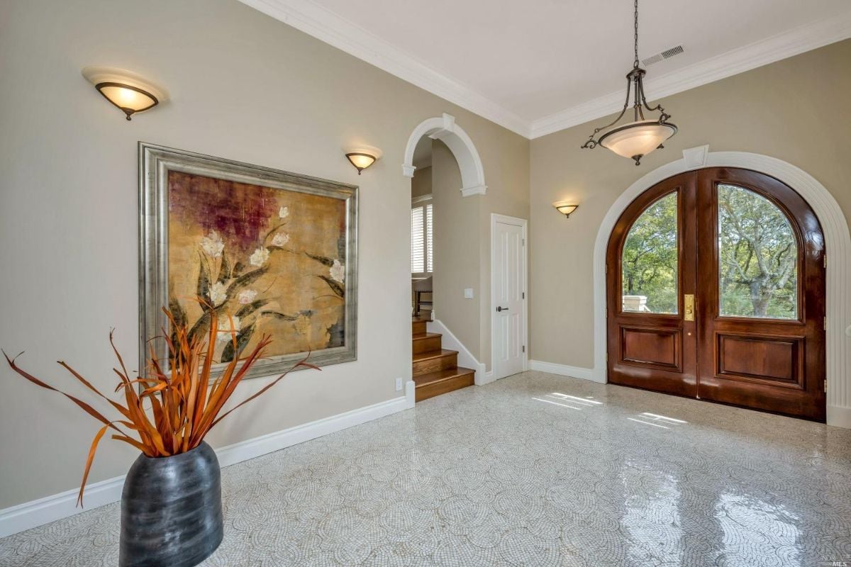 Large foyer with a large painting on the wall and marble tiles.