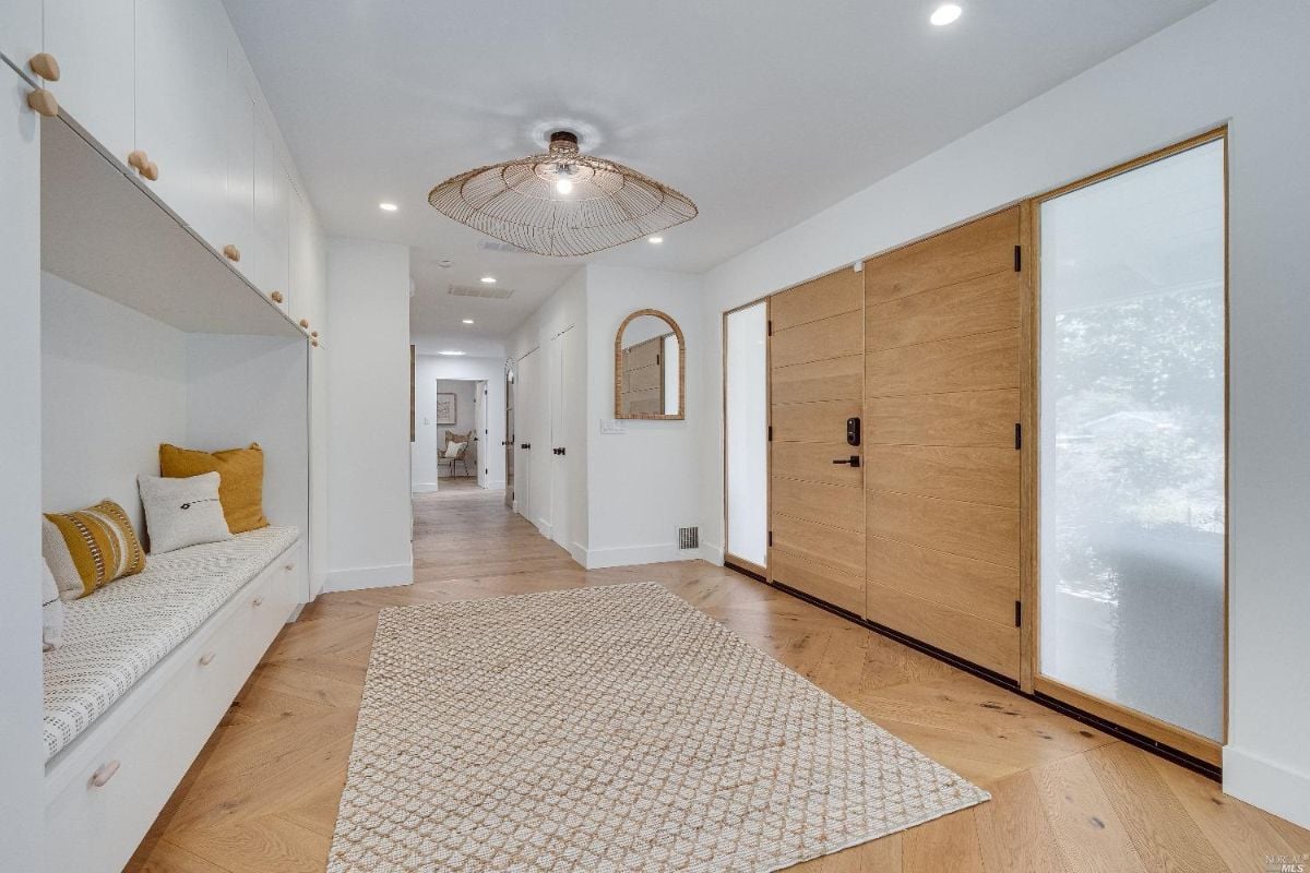 Foyer with a rug, wood floorings. and a built in bench.
